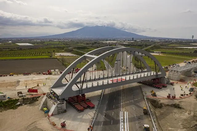 Ponte ad arco in costruzione sopra l’autostrada, con il Vesuvio sullo sfondo